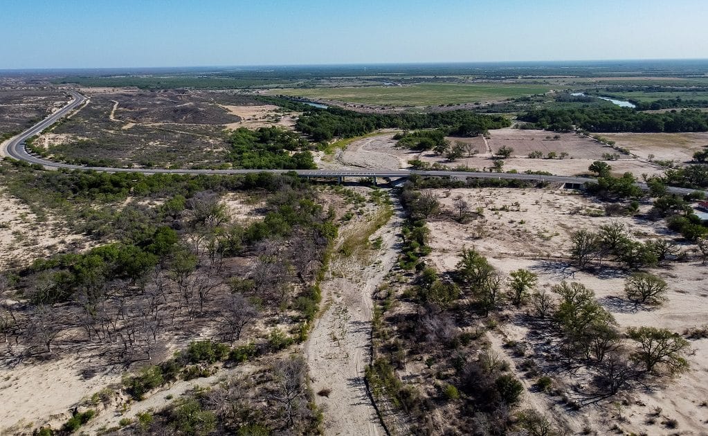  En primer plano el cauce seco del río San Rodrigo que debería aportar escurrimientos al río Bravo (al fondo de la imagen), pero que tiene al menos dos años que no lo hace, incumpliendo con un tratado internacional. Crédito: Omar Saucedo.
